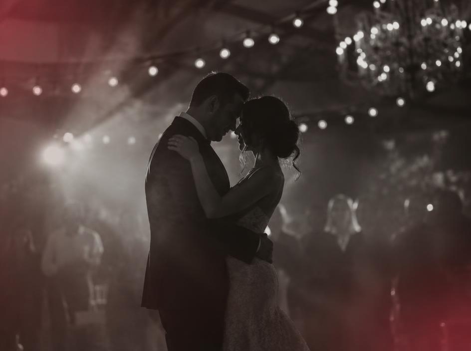 Couple sharing a first dance in soft haze at an evening wedding